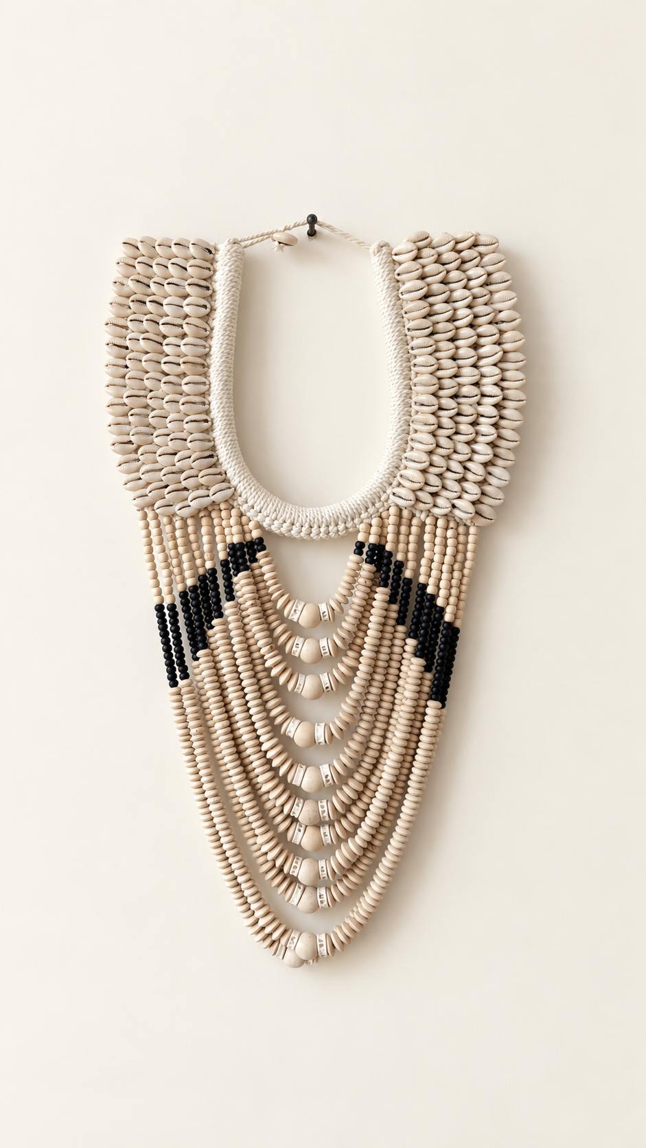 Layered Cowrie decorative shell necklace — Layered Cowrie Shell Necklace displayed on a clean warm cream wall