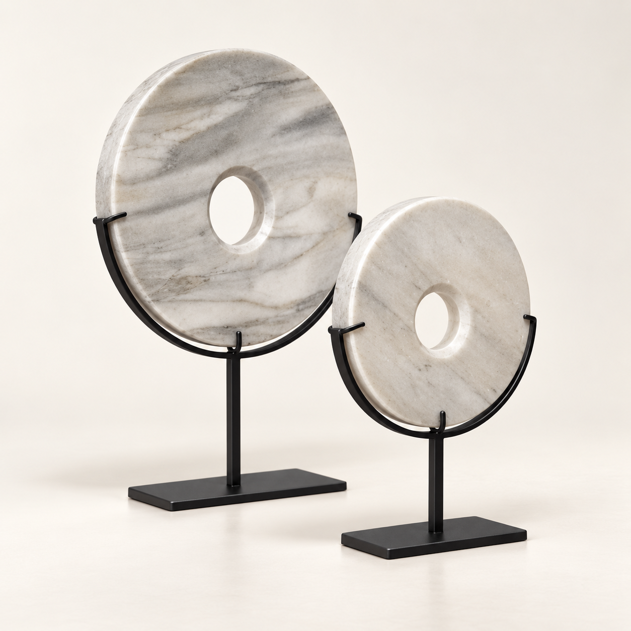 White natural stone disk sculptures on black metal stands, angled view