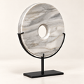 White natural stone disk sculpture showing natural veining