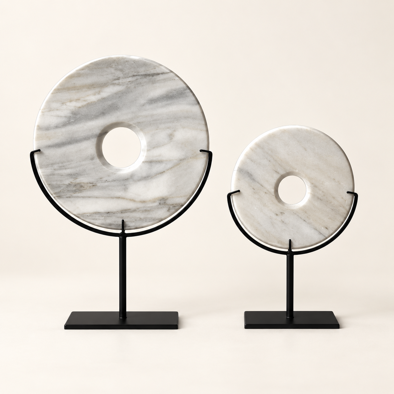 Two white natural stone disk sculptures on black metal stands