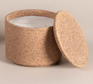 Brown textured candle jar with white wax and a matching lid leaning against the side
